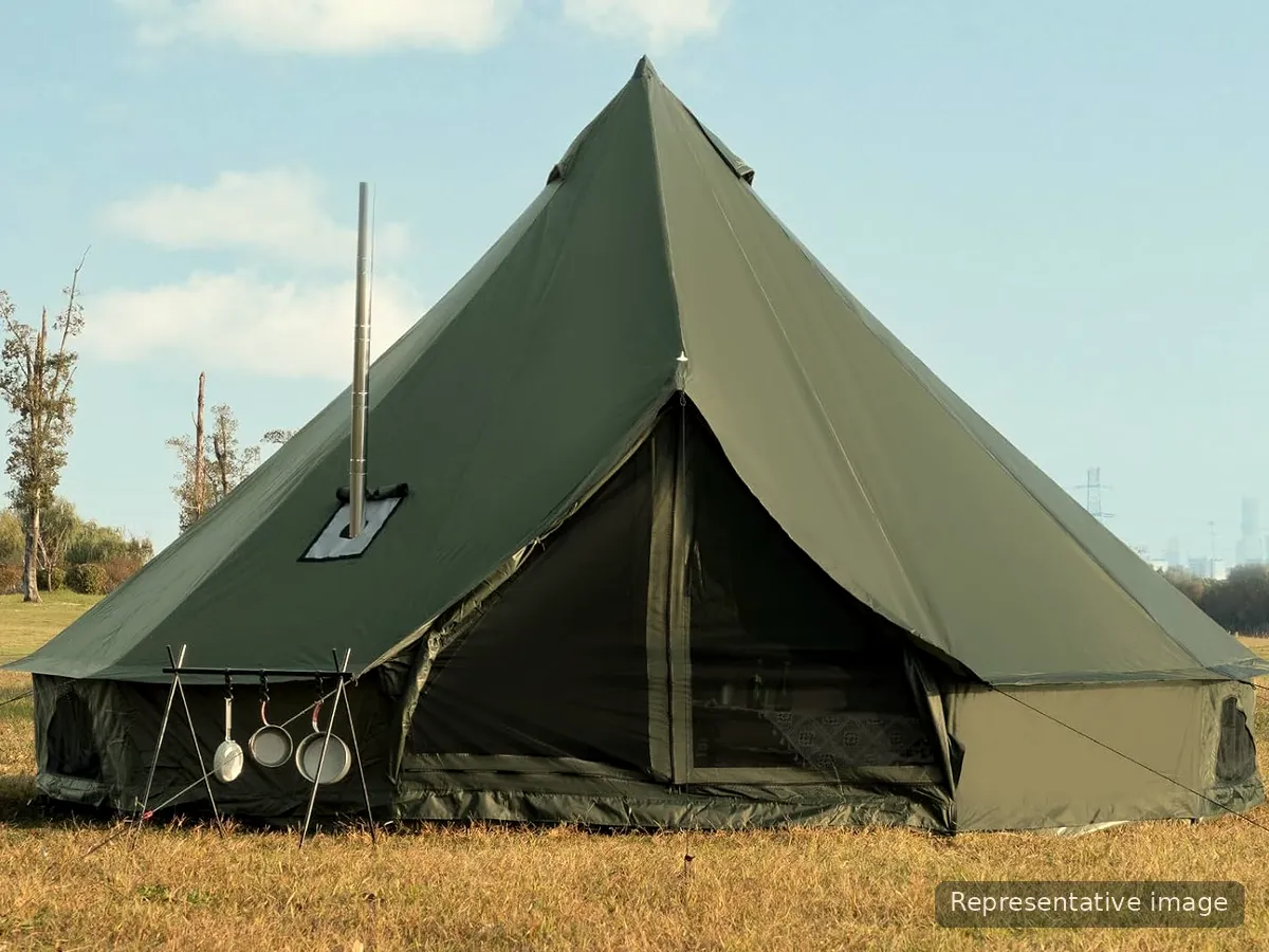 An olive-green 5 m canvas bell tent with a stove pipe, pitched on grass (manufacturer image)